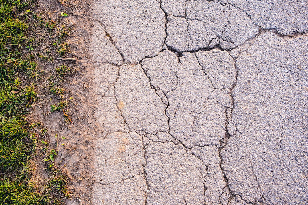 photo of a home asphalt driveway that is cracked and damaged
